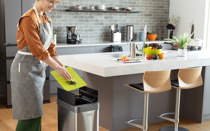 Người dùng bỏ rác vào thùng rác cảm biến EKO đặt cạnh đảo bếp